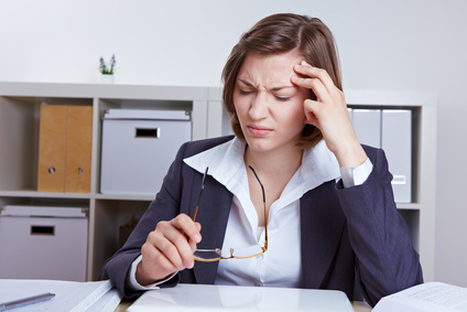 Geschäftsfrau sitzt mit Kopfschmerzen im Büro am Schreibtisch
